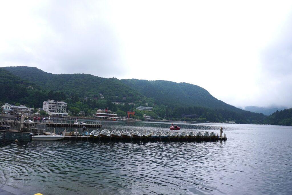 View of Lake Ashi with boats and the distant Hakone Shrine torii gate