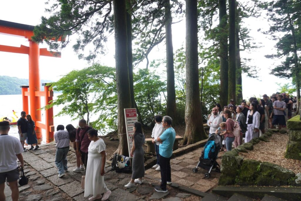 Visitors waiting in line to take photos at the famous lakeside torii gate