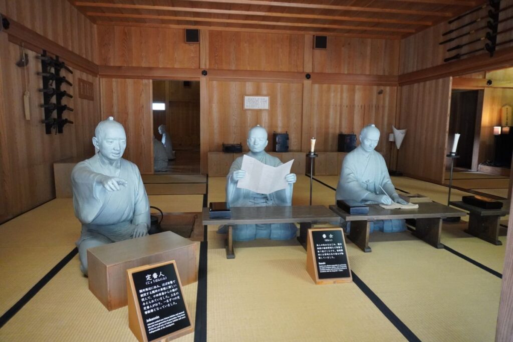 Officials inspecting a travel permit inside the reconstructed Hakone Checkpoint office.