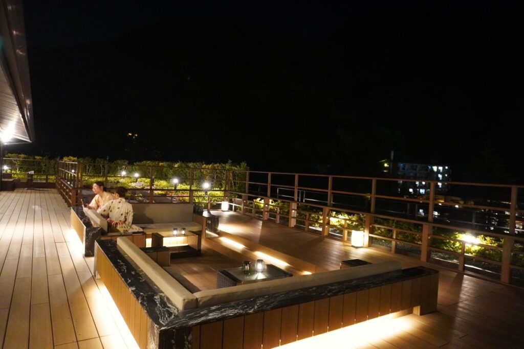 Guests relaxing in the rooftop sofa seats overlooking Hakone-Yumoto at Hotel Okada