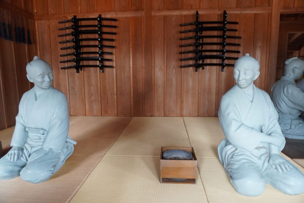 Edo-period foot soldiers resting with swords displayed on the wall at Hakone Checkpoint.