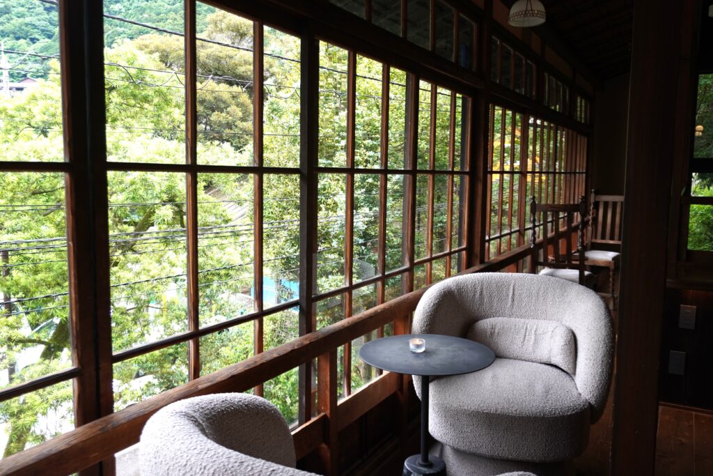 Cozy lounge with large wooden windows overlooking greenery in Hakone-Yumoto