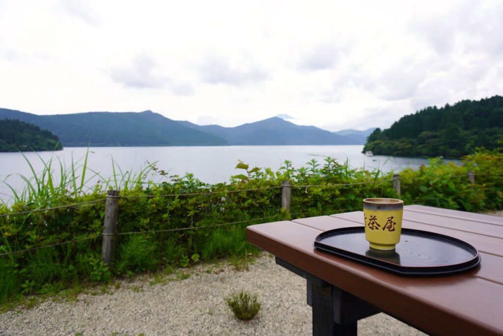 A cup of amazake served with a view of Lake Ashi and Mount Fuji.