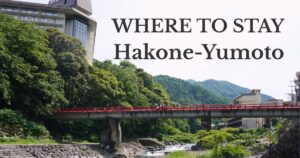 Red bridge over the Haya River with lush green mountains and hot spring hotels in Hakone-Yumoto, Japan