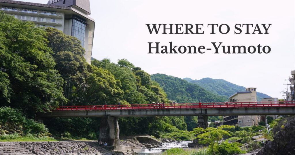 Red bridge over the Haya River with lush green mountains and hot spring hotels in Hakone-Yumoto, Japan
