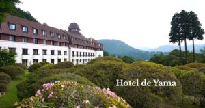 Hotel de Yama surrounded by beautifully maintained gardens in Hakone, with mountain views in the background