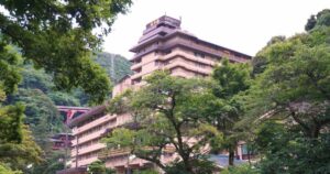 Exterior view of Hotel Okada, a large hot spring ryokan surrounded by the lush green mountains of Hakone.